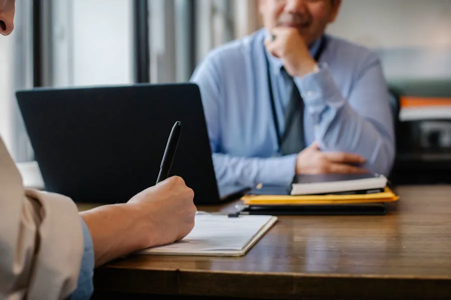 Twee mensen in gesprek aan een tafel met een laptop